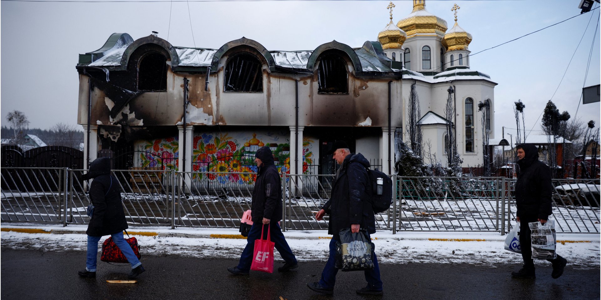 Люди проходять повз пошкоджену обстрілами будівлю, тікаючи від російських військ, що&nbsp;наступають. 8 березня 2022 року (Фото: REUTERS/Thomas Peter)