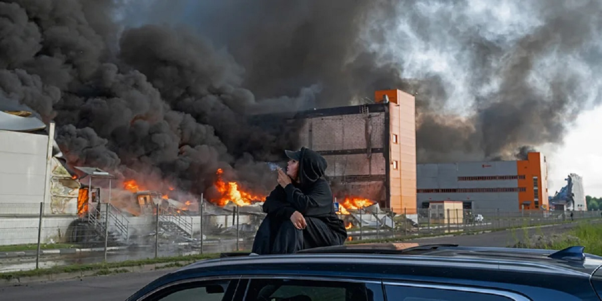 A woman watches a fire at a Wildberries warehouse near the village of Novosaratovka in the Leningrad region following a Ukrainian drone attack on July 24, 2026 (Photo: SOPA Images via Reuters)
