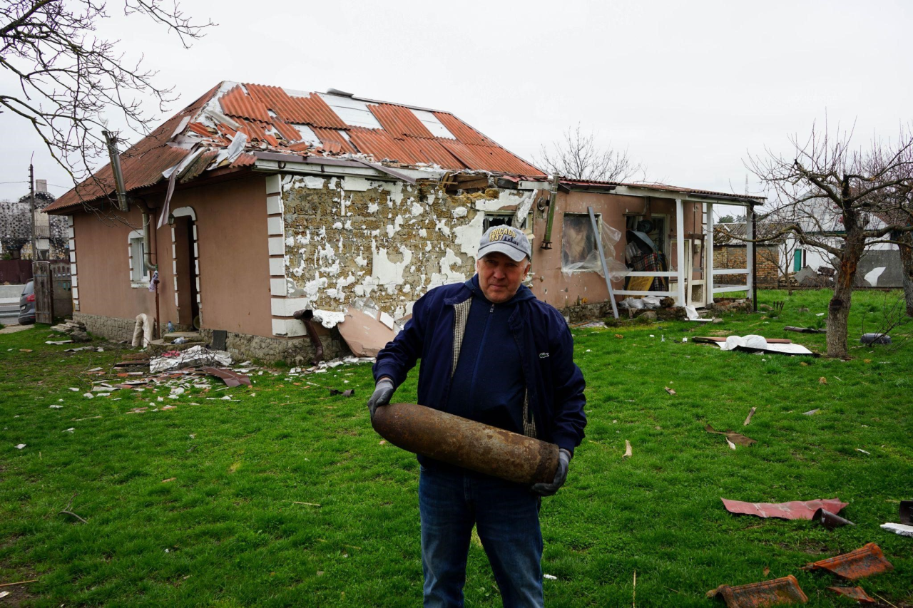 Oleksander with a WW2-era German shell in front of his sister’s destroyed house (Фото: Anthony Bartaway/NV)