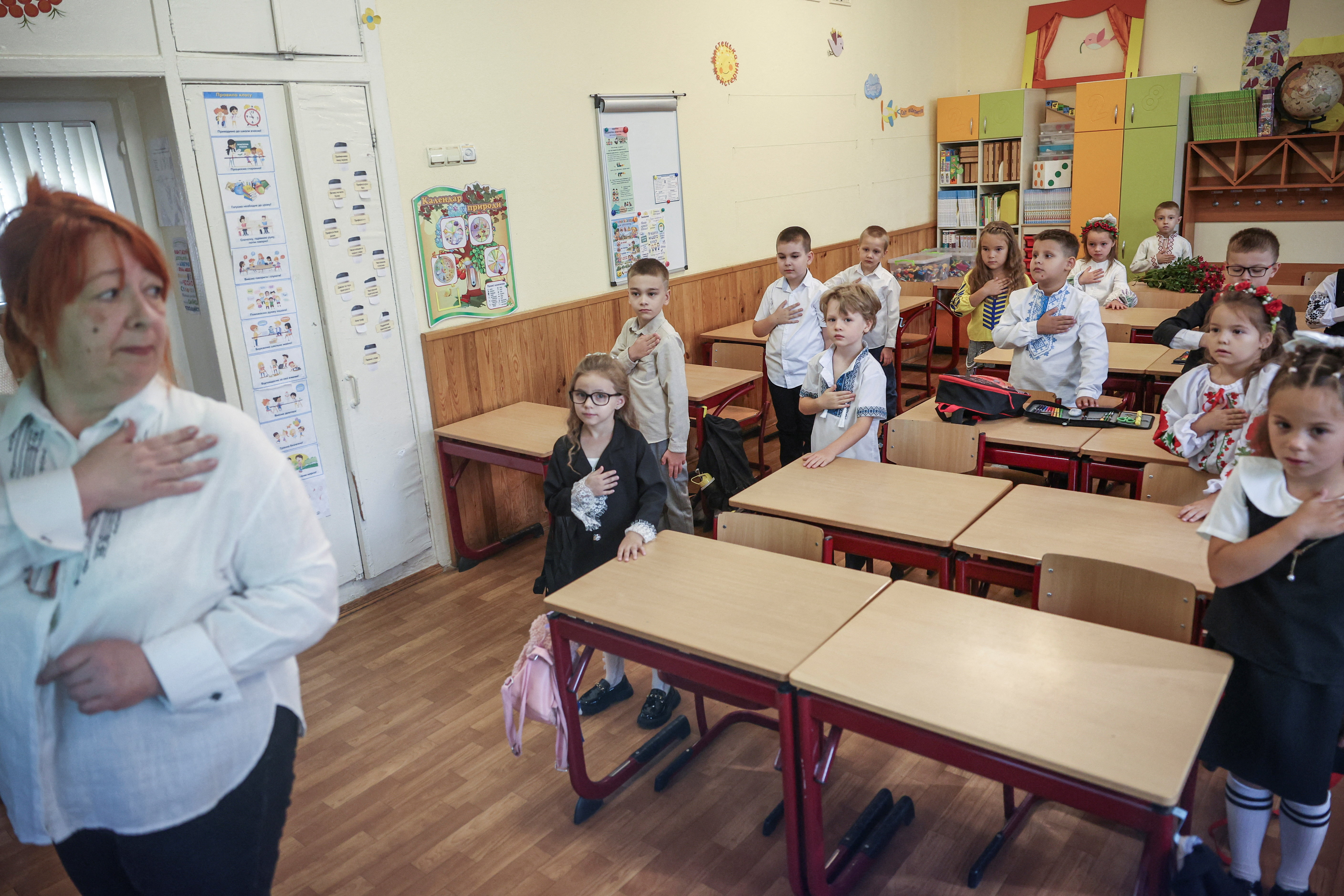 Вчителька першокласників Анна показує дітям, як слід поводитися під час виконання гімну України у перший день нового навчального року (Фото: REUTERS/Alina Smutko)